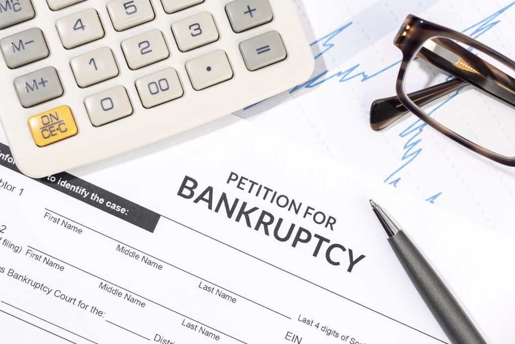 Bankruptcy form, calculator and pen on desk.